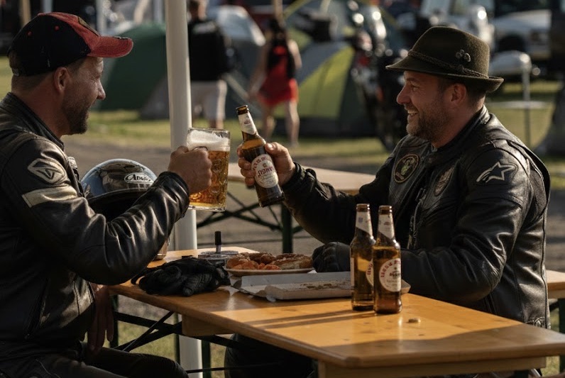 Motorradfahrer stoßen am Holztisch an – Gemeinschaft und steirische Gastfreundschaft nach dem Training am Red Bull Ring