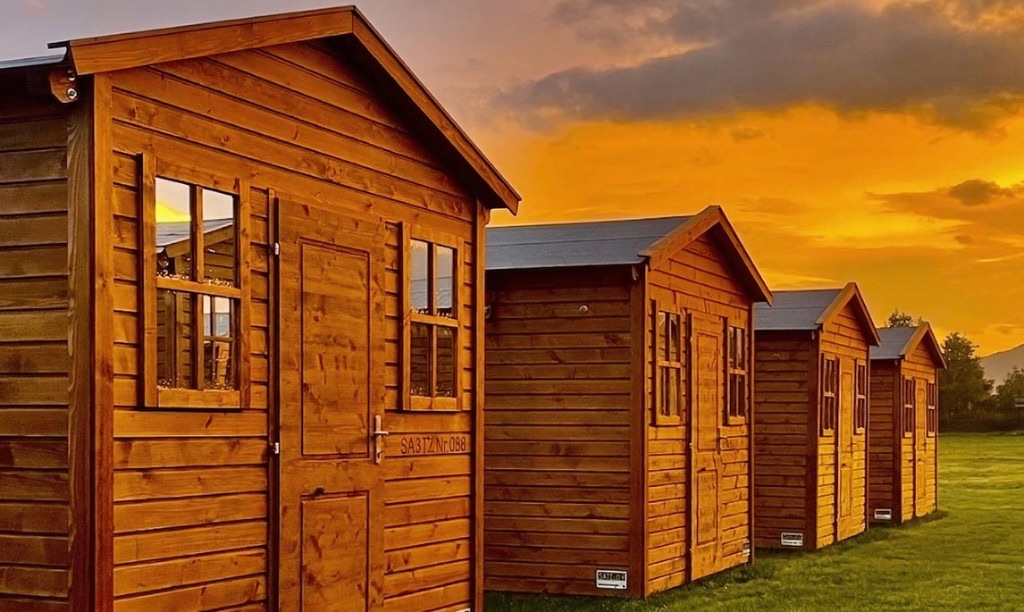 Glamping Holz-Chalets in einer Reihe bei Sonnenuntergang – Schitterhof CAMPING WEISS Spielberg, MotoGP Grand Prix Österreich am Red Bull Ring
